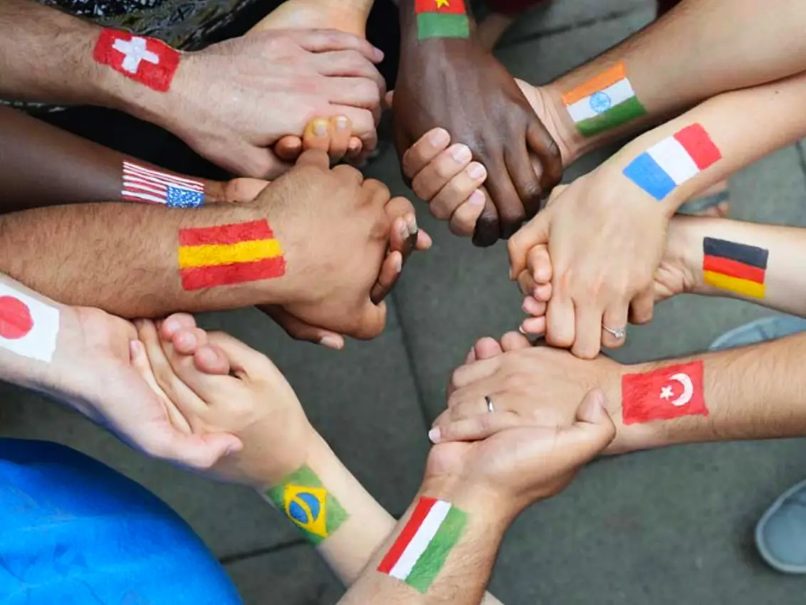 hands joined with different country flags painted on the wrist to signify unity