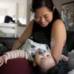 Mujer asiática con un niño en brazos y sonriendo.