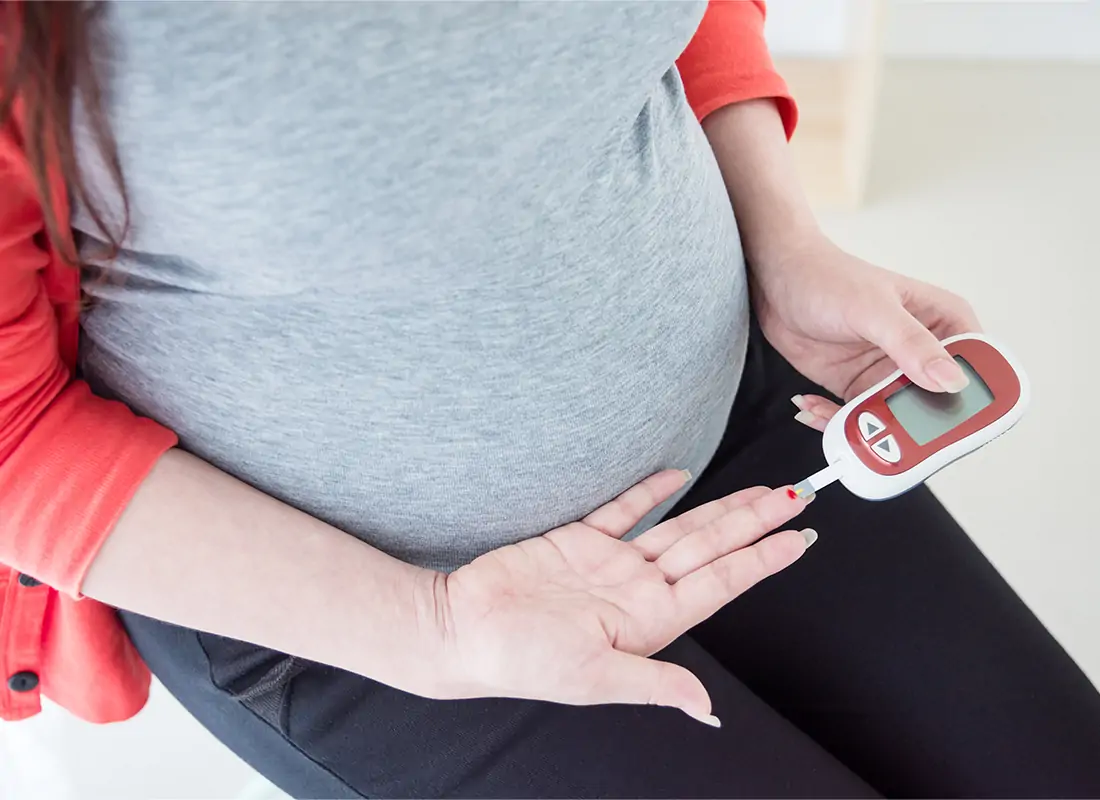 Pregnant woman checking her blood glucose to manage gestational diabetes.