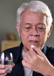 Elderly man about to take a pill with glass of water