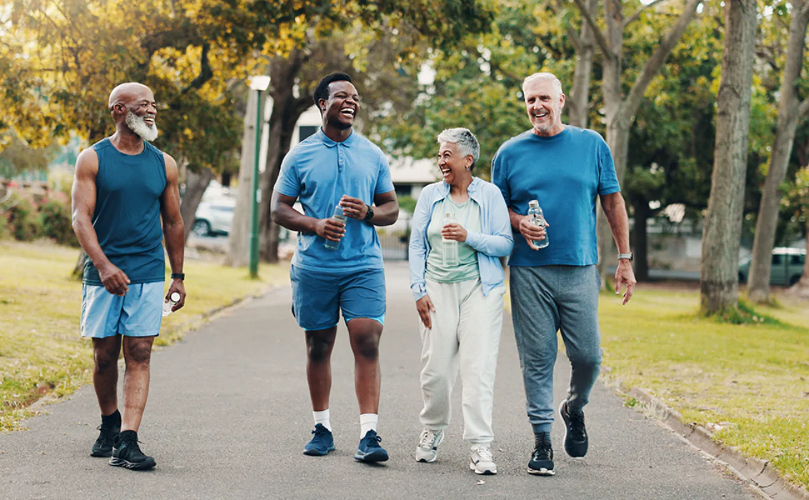 Group, people and walking for fitness outdoor of mobility training, discussion and morning routine. Smile, senior community and coach laughing for exercise joke, funny chat and cardio workout at park